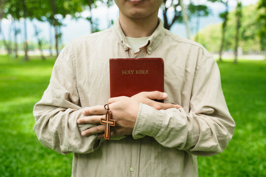 The concept of reading the Bible and praying to God for blessings, living peacefully in nature and spending time with God, with a hand holding a Bible.