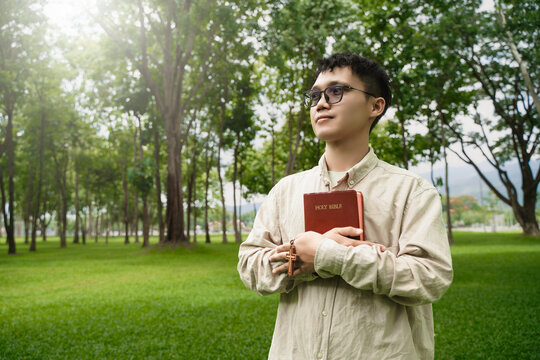 The concept of reading the Bible and praying to God for blessings, living peacefully in nature and spending time with God, with a hand holding a Bible.