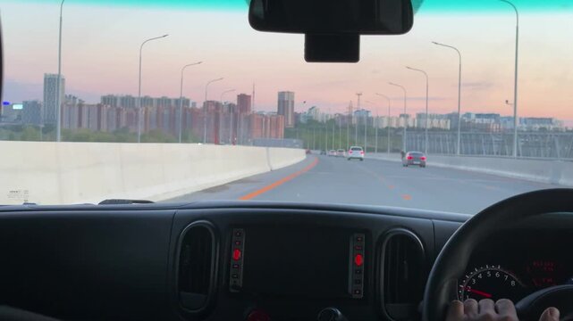 Taxi driver driving car on beautiful cable bridge at sunset. View from interior of vehicle, person steering wheel while traveling on highway. Automotive transport, road trip and commute concept.