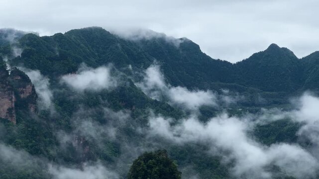 Avatar Mountains range covered with thick fog and green trees. Majestic cliffs Wulingyuan national forest park Zhangjiajie. Geological landscape, natural scenery travel, adventure outdoor trip.