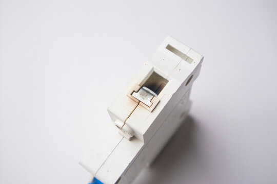 High-angle, close-up shot focusing on the top terminal section of a white miniature circuit breaker, displaying signs of heat discoloration and oxidation on the internal metallic connector