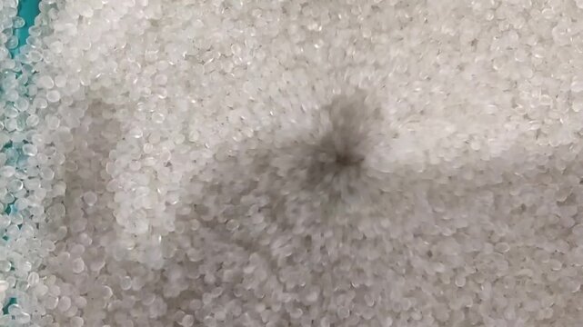 the vortex process of the falling movement of clear polymer plastic granules that pile up from the container for packing