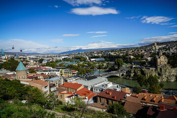 Fototapeta premium Scenic elevated view of Tbilisi, Georgia, highlighting Metekhi Church, Mtkvari River, and the iconic Peace Bridge.