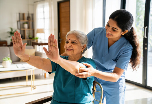 Indian caregiver assisting senior woman arm stretching exercise home healthcare modern living room natural light