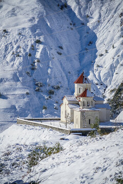 Gergeti Trinity Church with red roofs, snow-covered in Caucasus mountains near Stepantsminda, Georgia.