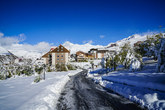 Snow-covered Gudauri ski resort village with Caucasus Mountains under a vibrant blue winter sky, Georgia.