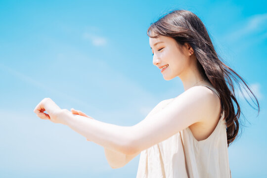 海で日焼け止めを塗る若いアジア人女性