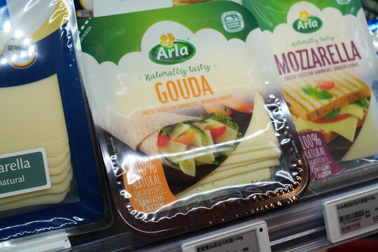 Packaged Arla cheese slices displayed on a supermarket shelf.