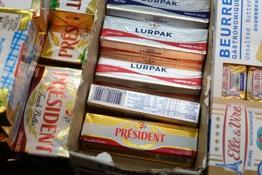 Assorted imported butter packages displayed on a supermarket shelf.