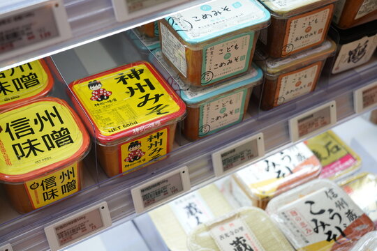 Assorted Japanese miso paste containers on a supermarket shelf.