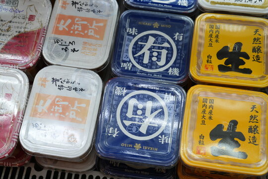Assorted Japanese miso paste containers on a supermarket shelf.