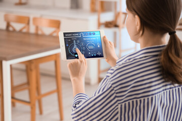 Woman controlling smart home system on tablet indoors © Pixel-Shot