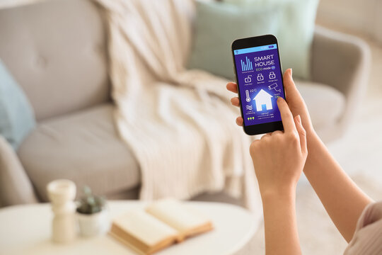 Person controlling smart home system on smartphone indoors
