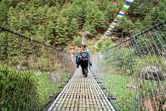 Mujer cruzando puente colgante en su camino al campamento base del Everest, en Nepal.