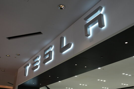 A large glowing Tesla sign inside a retail showroom.