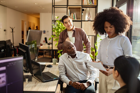 Coworkers reviewing documents during team meeting in modern office