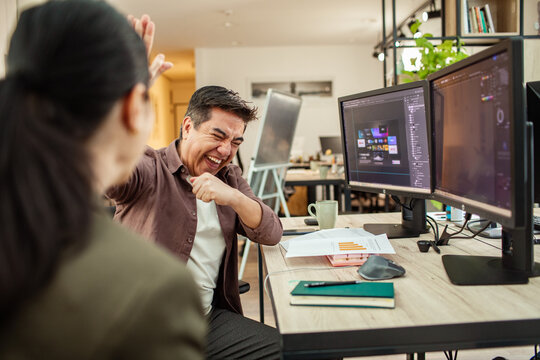 Coworkers celebrating project success at modern creative office desk