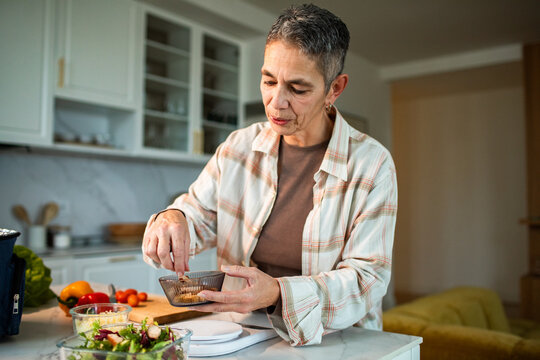 Senior woman preparing salad dressing in home kitchen