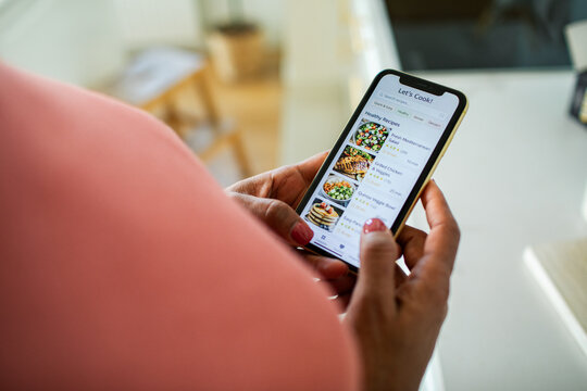 Person browsing healthy recipe app on smartphone in home kitchen