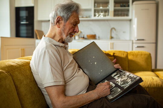 Elderly man looking through photo album at home