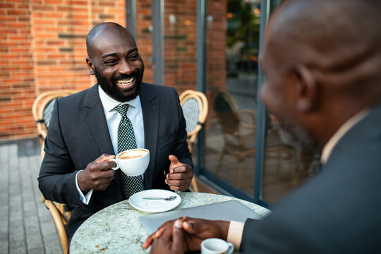 Two businessmen meeting over coffee at outdoor cafe
