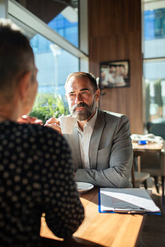 Mature businessman having coffee during meeting at cafe