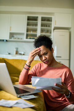 Concerned woman reviewing household bills in home kitchen
