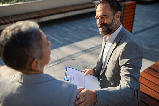Business colleagues discussing report outdoors in urban courtyard