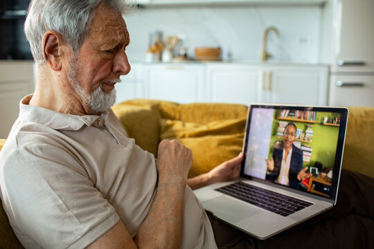 Senior man video chatting on laptop at home