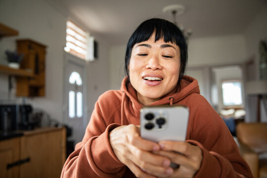 Smiling woman video chatting on smartphone at home