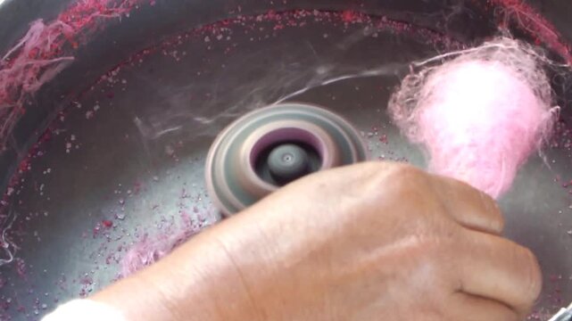 close up hand of a hawker making sweet cotton candy. Attraction of a snack seller for kids. 