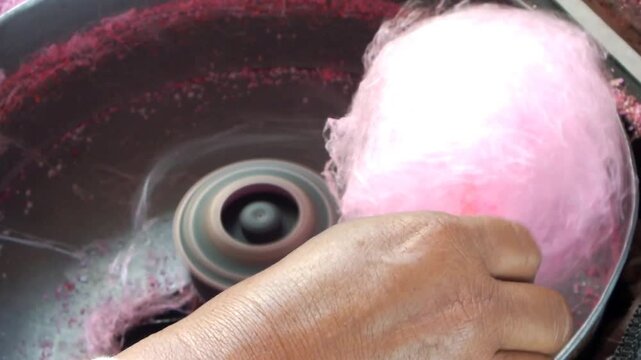 close up hand of a hawker making sweet cotton candy. Attraction of a snack seller for kids. 