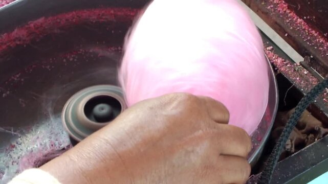 close up hand of a hawker making sweet cotton candy. Attraction of a snack seller for kids. 