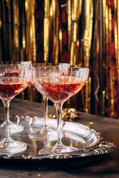 Sparkling ros&eacute; champagne poured into vintage coupe glasses against a shimmering gold backdrop, evoking festive celebration, glamour and toasts at parties,  Christmas, weddings and New Year gatherings.