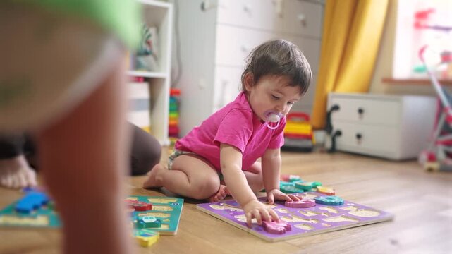 baby daughter plays with toys on floor develops fine motor skills. Mom plays with her baby daughter, teaches her to put pictures into slots. lifestyle happy family kid dream concept