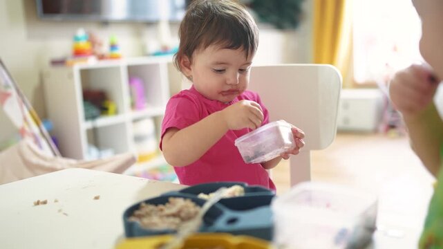grimy baby eats at table. baby learns to eat develops fine motor skills gets his face dirty. happy family kid lifestyle dream concept. baby blond daughter eats dirty
