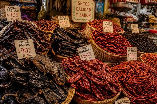 Market stall overflowing with various dried chilies, including ancho peppers.