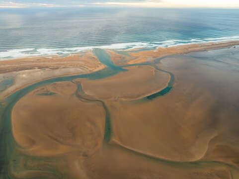 Aerial view of Raudisandur beach with intricate tidal channels and golden sands meeting the Atlantic Ocean in Vesturbyggd, Iceland.