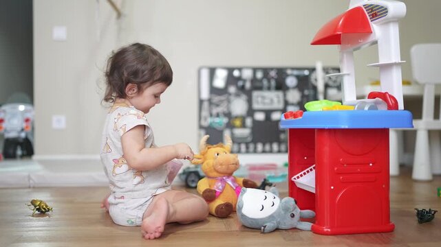 baby plays in toy kitchen and feeds the animals. happy family kid dream concept. baby feeds toys in the kitchen plays cook. baby plays with toy kitchen lifestyle and prepares food