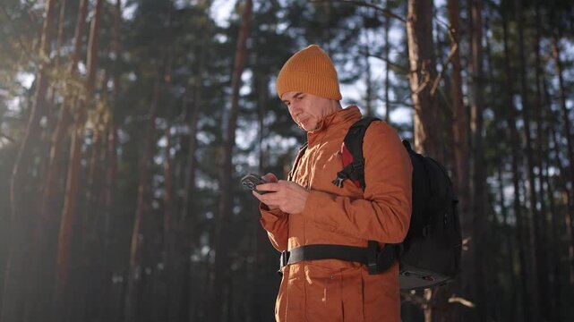 travel navigation. man tourist looking for a way in a smartphone navigation in winter in forest park. male hacker navigates in close-up the forest navigation looking for a way in winter in park