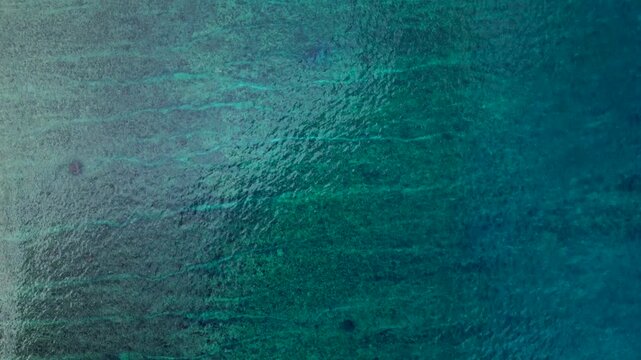 Overhead perspective ocean waves breaking over shallow coral reef. dMagic aerial view rone