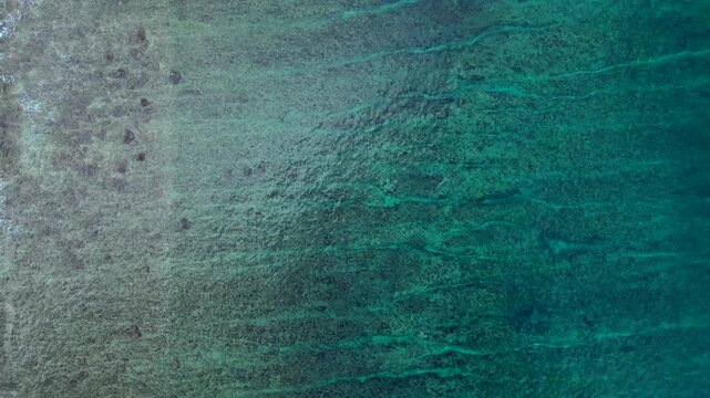 Overhead perspective ocean waves breaking over shallow coral reef. Best aerial view drone