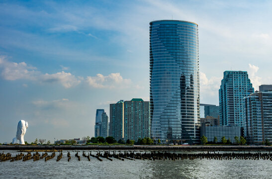 Hoboken, NJ - US - Jul 1, 2026 the Jersey City skyline viewed across the Hudson River from Hoboken, highlighting the 41-story Ellipse rental tower and Jaume Plensa's 80-foot Water's Soul sculpture.