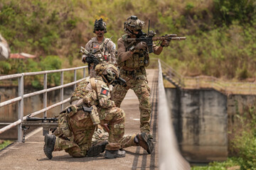 Fototapeta premium Soldiers conduct tactical training on a bridge during the day with focus on teamwork and coordination