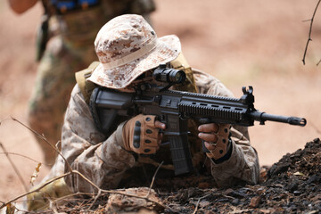 Fototapeta premium Soldier practices shooting skills in military training area during bright daylight hours
