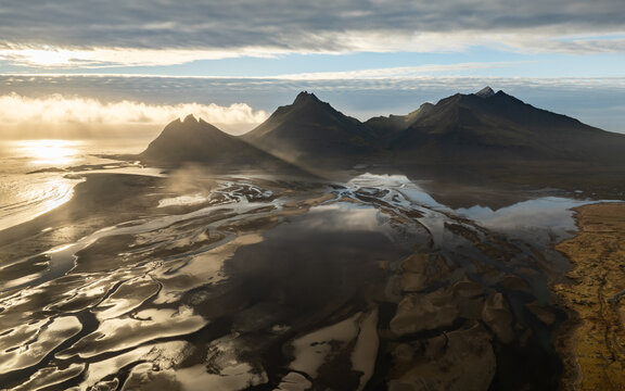 Aerial view of Stokksnes and the dramatic Vestrahorn mountain reflecting in the tidal flats under a golden hour sky in Iceland.