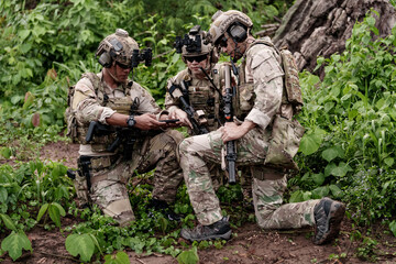 Fototapeta premium Soldiers review plans in a forest while preparing for a mission during day time