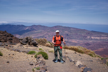Fototapeta premium Hiker with trekking poles on mountain trail