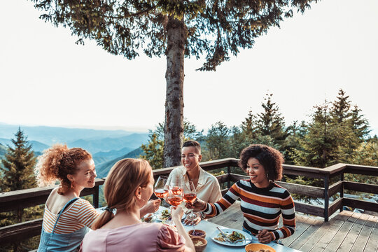 Friends toasting wine during outdoor dinner on mountain cabin deck