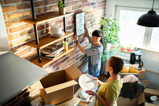 Two people unpacking and decorating in a bright apartment kitchen